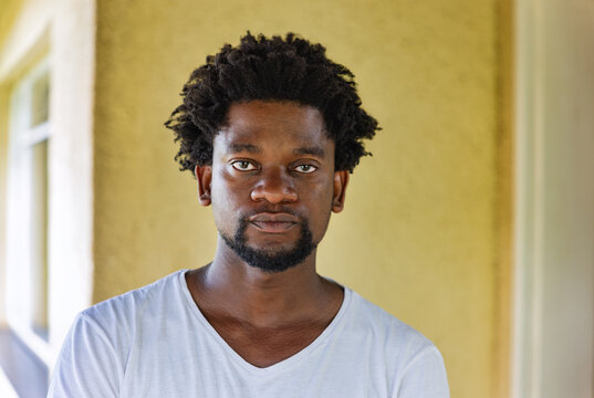 Portrait of a Smiling Young African Man with an Afro Hairstyle blurred green outdoor background.