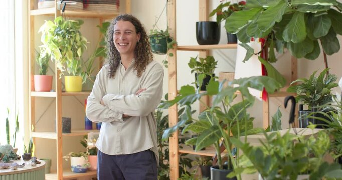 Adult nonbinary African standing crossing arms smiling and reacting to offframe voice in plant shop