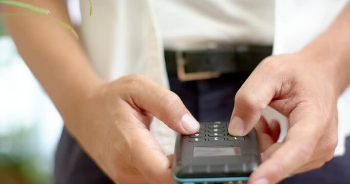 Nonbinary African in shirt starting with thumbs hovering, holding keypad, tapping numbers at desk