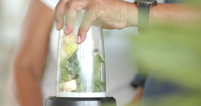 African American couple at home counter, male hand pressing jar on blender, blending smoothie