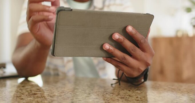 Adult African American man holding tablet, adjusting folio and tapping screen at granite counter