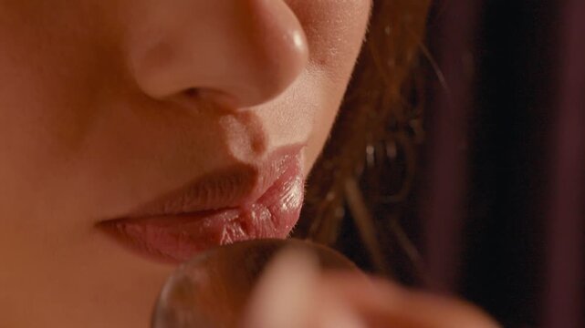 Close-up of a woman eating a bite of food. Detail of lips and mouth, hand bringing food close, soft warm lighting and blurred background. Tasting, appetite and dining concept
