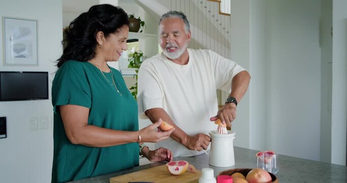 Woman is handing grapefruit half, man is pressing and rotating juicer to extract juice on island