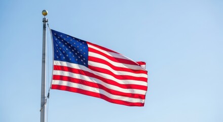 Fototapeta premium American flag waving on flagpole against clear blue sky, United States national flag with stars and stripes, patriotic symbol of freedom and democracy
