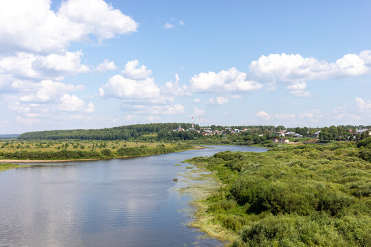 View to river with boggy banks, lush vegetation, Sovetsk town, Kirov region, Russia under blue sky