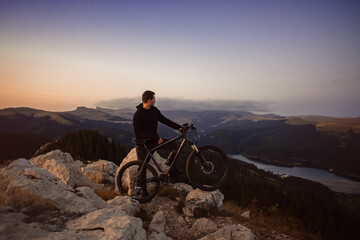 Fototapeta premium Man relaxing with mountain bike enjoying sunset view