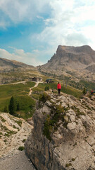 Fototapeta premium Woman standing on cliff edge enjoying dolomites mountain view