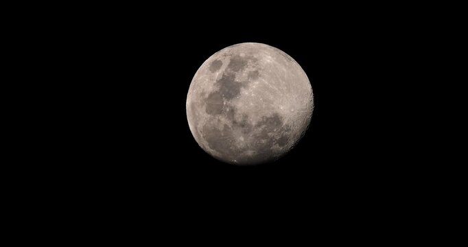 Full moon shining in a clear black night sky showing detailed lunar craters and surface texture. Close-up telephoto shot of the moon during night.