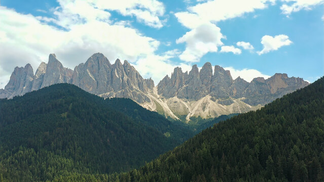 Odle group mountains towering above green forest landscape
