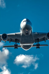 Naklejka premium A Boeing 737 or similar aircraft soaring through a clear blue sky with white clouds. vertical frame