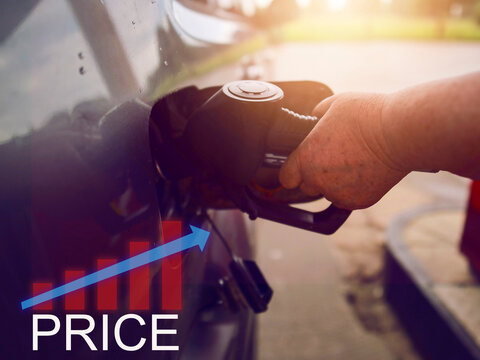 Old mature woman hand is filling up her car fuel tank, sign price and up going graph show rising cost of travel for people living on pension. Diesel and petrol price going up during crisis.