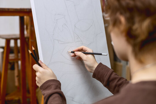 A female artist paints a still life from life. An easel with a sketch in an art studio. 