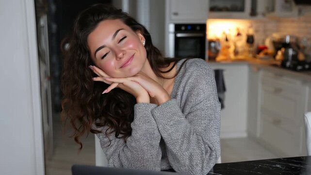 Ute young woman smiling while sitting at home table with laptop in cozy kitchen during a relaxed morning