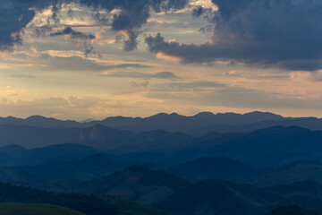 Fototapeta premium Layered Mountain Range Under Dramatic Cloudy Sky at Dusk