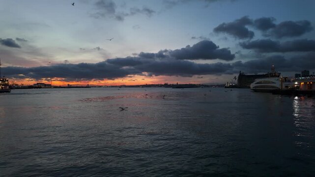 Sunset over the water with boats and distant buildings at the harbor