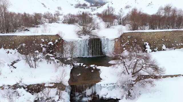 Snow blankets quiet winter forest with rocky stream