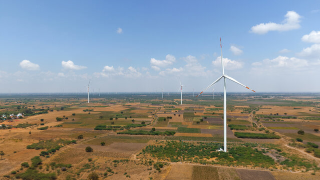 Wind turbines across agricultural fields in rural landscape aerial view