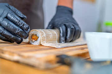 Hands rolling maki sushi on bamboo mat © Guillermo Spelucin