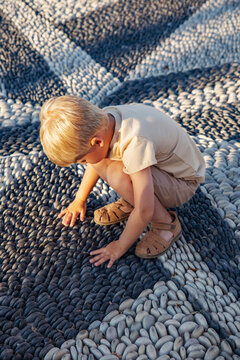 Curious boy exploring pebbles in the sunlight