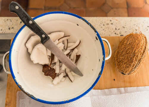 Preparing fresh coconut with knife in kitchen