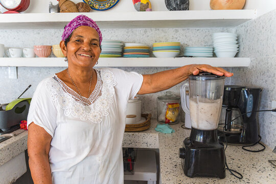 Caribbean woman blending tropical ingredients in kitchen