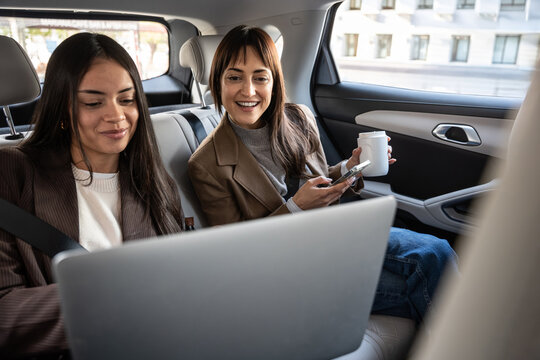 Businesswomen working with laptop in car during commute