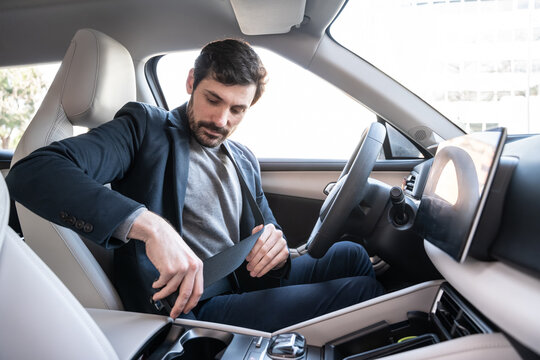 Businessman fastening seat belt inside modern car interior