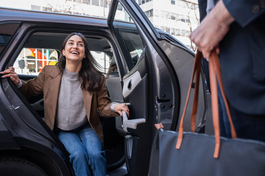 Smiling woman stepping out of a car with city background