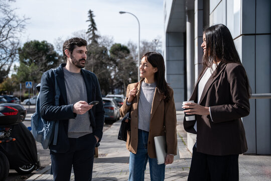 Business team chatting outdoors during breaktime with coffee