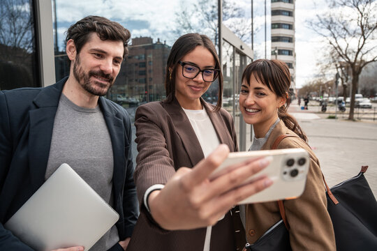 Business colleagues taking selfie outside modern office