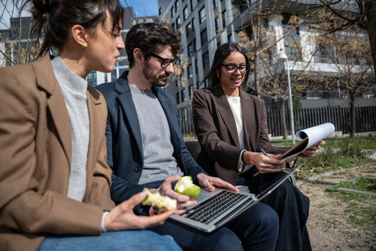 Business colleagues meeting outdoors with laptop and apple