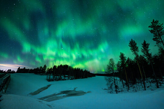 Aurora borealis over frozen lake and forest in Finland