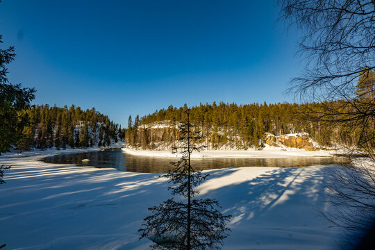 Winter river bend in Finland with forest and blue sky
