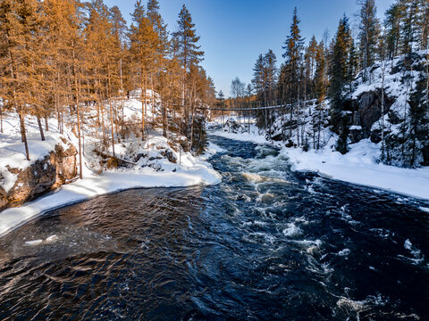 Winter river rapids through snowy forest canyon in Finland
