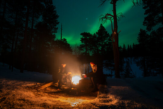 Aurora borealis over winter campfire in Finnish forest