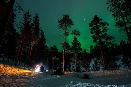 Winter campfire under northern lights in Finland forest