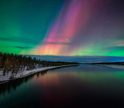 Northern lights over a frozen river landscape in Finland