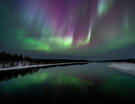 Northern lights over frozen river landscape in Finland