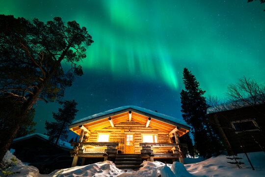 Northern lights above a snowy log cabin in Finland