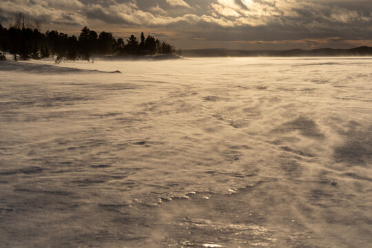 Windswept snowy lakeshore at sunset in Finland winter