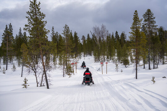Snowmobile riders on a snowy forest trail in Finland