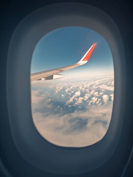 Aerial view through airplane window with wing visible