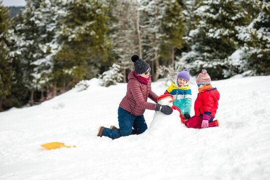 Family having fun building a snowman in winter