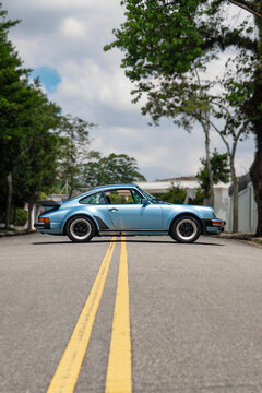 Blue Porsche 930 Turbo full side profile view outdoors, Classic sports car silhouette on city street