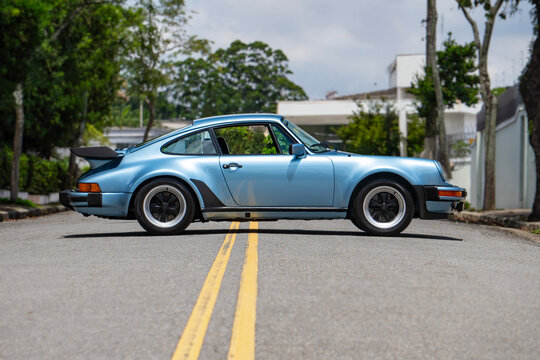 Blue Porsche 930 Turbo full side profile view outdoors, Classic sports car silhouette on city street