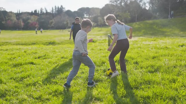 Boy falling while playing soccer with friends in a park
