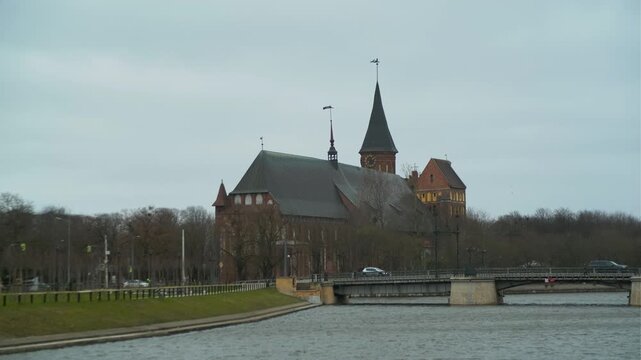 Cathedral on the river bank. Old gothic brick church with tall spire. Historical architecture in Kaliningrad, Russia. Travel destination and cultural landmark for tourism exploration.