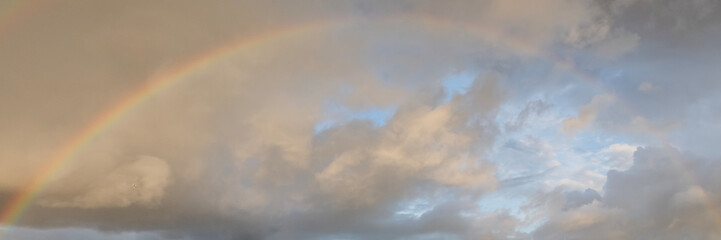Obraz premium a rainbow in the sky with scattering clouds after rain