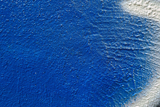 Grunge blue stucco wall with white painting strokes and spray