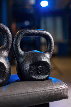 Black kettlebell with 8 marking on padded rack in gym with moody lighting and shallow focus